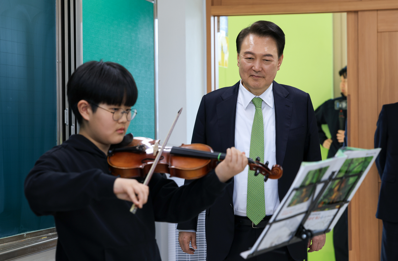 윤석열 대통령이 지난 21일 강원도 원주시 명륜초등학교 늘봄학교에서 바이올린 연주 프로그램을 참관하던 모습. [연합]
