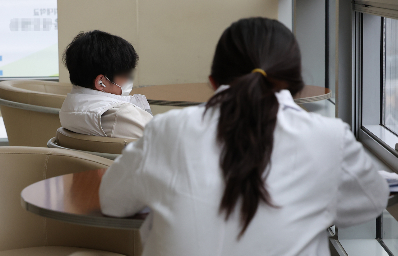 전공의 집단행동이 이어지고 있는 29일 오후 서울 시내 한 대형병원에서 한 의사와 내원객이 휴식을 취하고 있다. [연합]