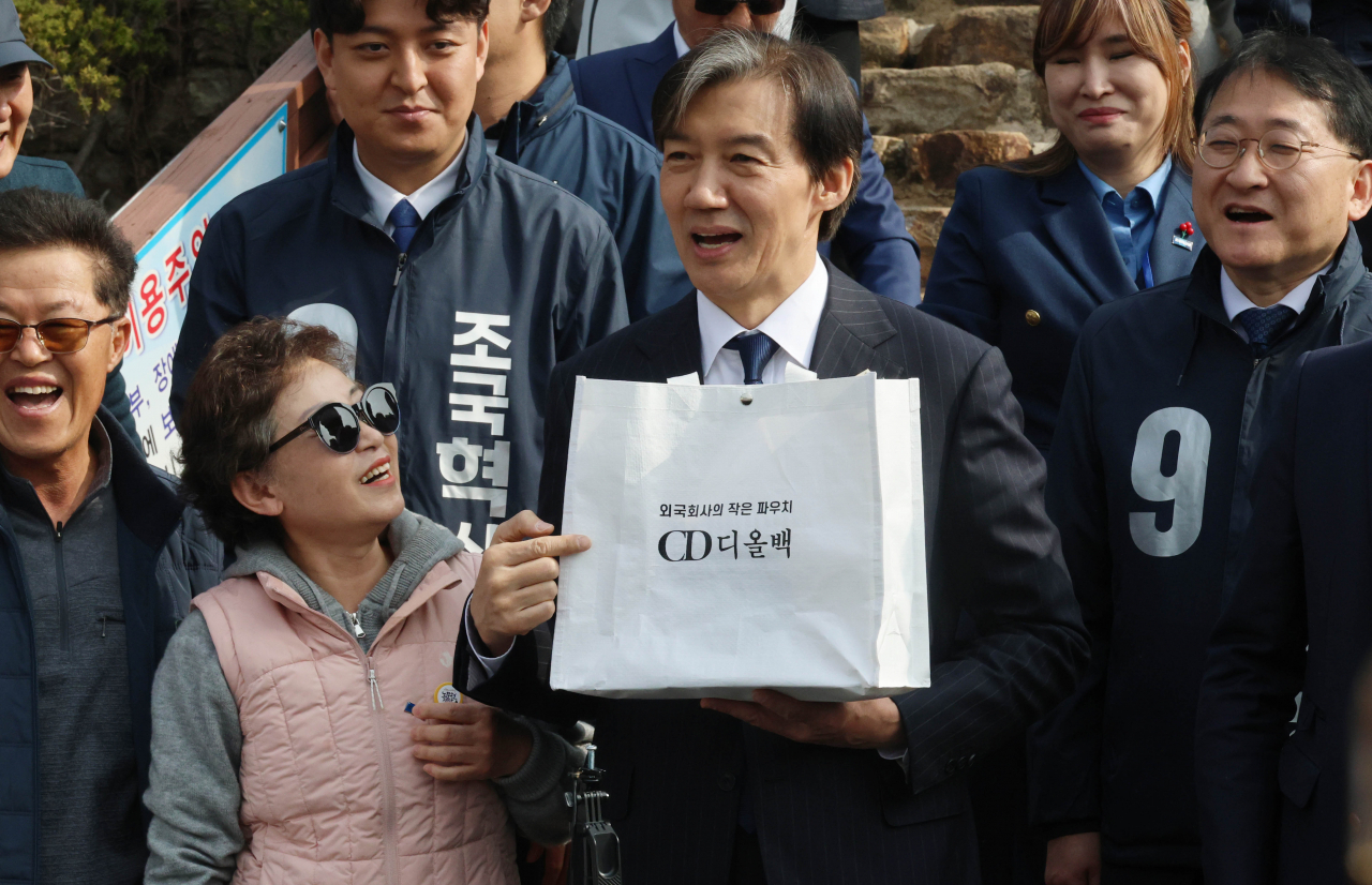 31일 경남 거제시 김영삼 전 대통령 생가를 찾은 조국혁신당 조국 대표가 한 지지자로부터 '외국회사의 작은 파우치 CD 디올백'이라고 적인 가방을 받은 뒤 웃고 있다. [연합]