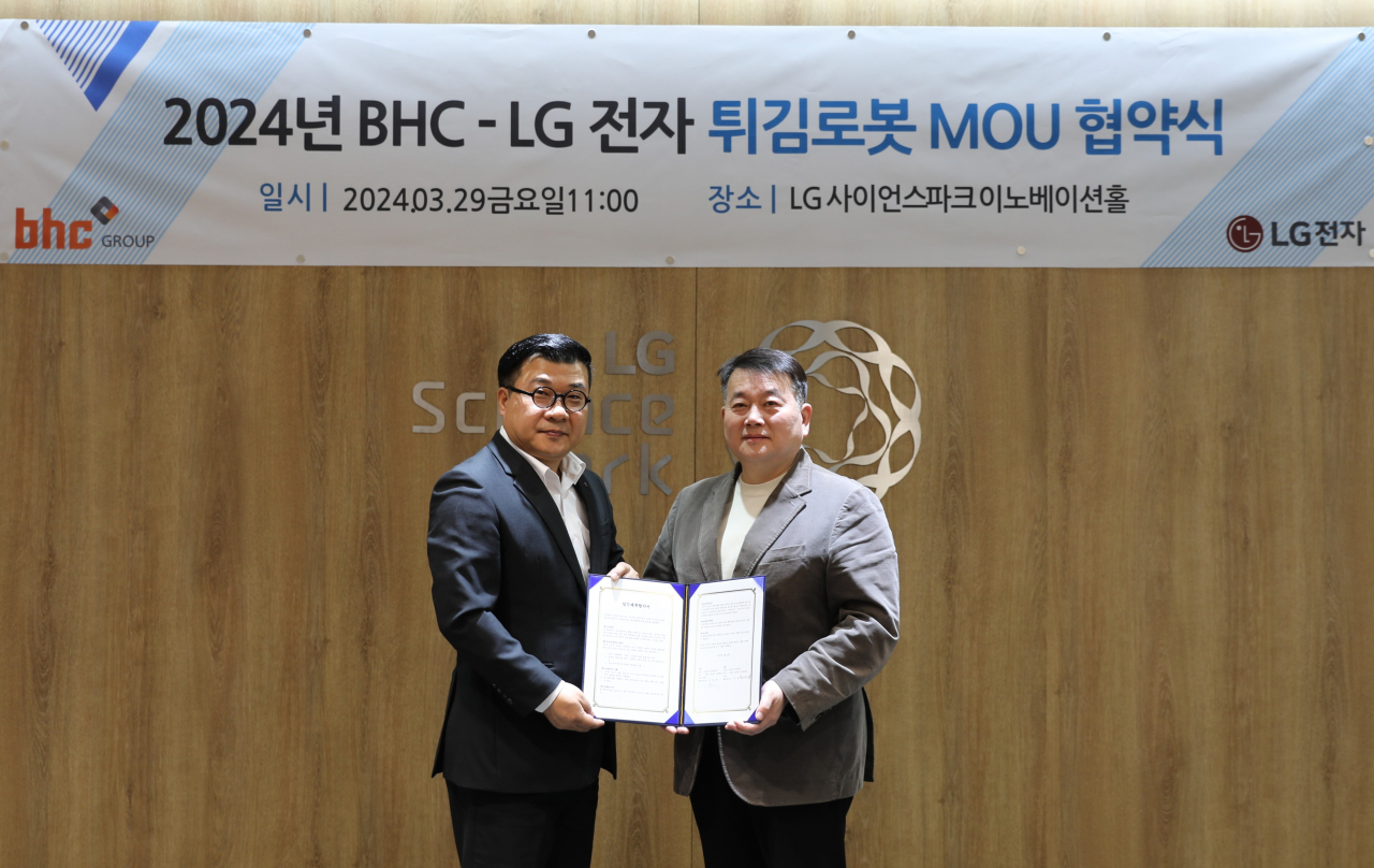 서영덕(왼쪽) LG전자 커머셜기업1담당 상무와 문상만 bhc 가맹사업본부장이 ‘튀김로봇’ 공동 사업 MOU 체결 기념사진을 촬영하고 있다. [bhc치킨 제공]