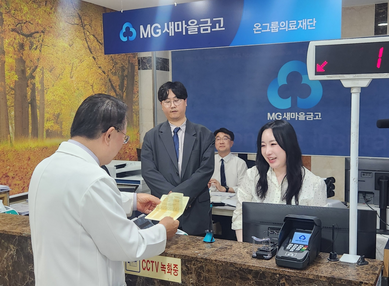 부산 온그룹의료재단 새마을금고가 8일 오전 부산 부산진구 당감2동 온종합병원 1층 점포에서 본격 영업을 시작한 가운데 김동헌 초대 이사장이 통장을 개설하고 있다. [사진=온그룹의료재단]