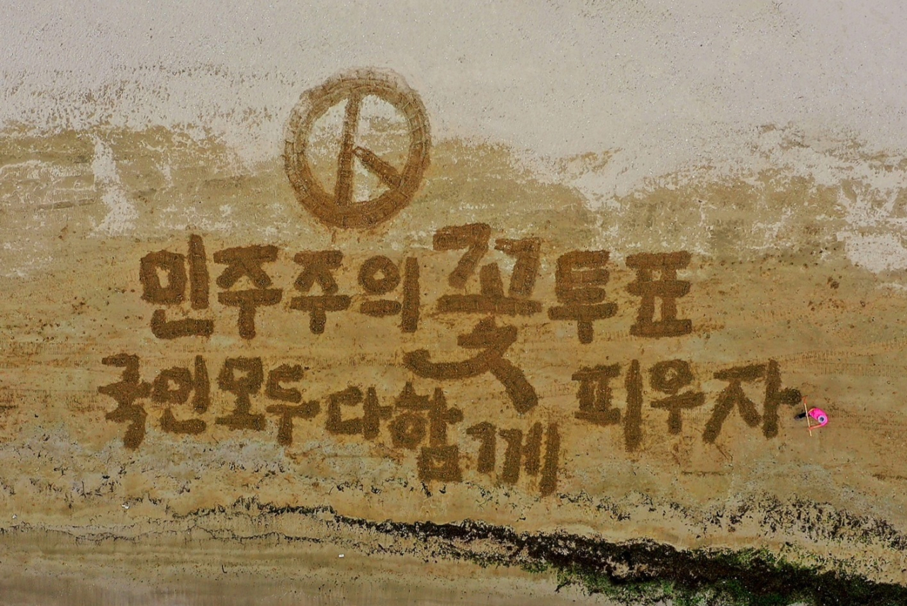 쌍산 김동욱 서예가가 제22대 총선을 이틀 앞둔 8일 포항시 송도 해수욕장에서 투표 독려 퍼포먼스를 하고 있다. 연합뉴스