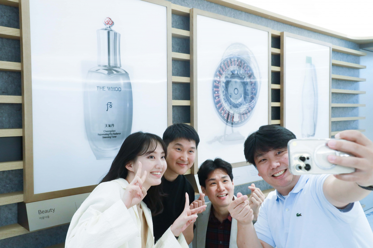 LG 직원들이 서울 여의도 LG트윈타워에서 LG의 과거와 현재를 함께 조명한 작품을 배경으로 사진을 찍고 있다. [LG 제공]