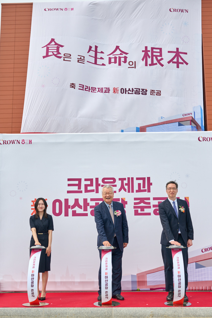 지난 4월 30일 크라운제과 신(新)아산공장 준공을 기념해 윤영달 크라운해태제과 회장(가운데)과 윤석빈 크라운제과 대표이사(오른쪽), 신입사원 손유리 사원(왼쪽)이 제막식 행사를 하고 있다. [크라운제과 제공]