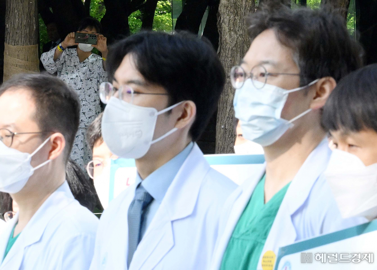 서울 아산병원 소속 교수들이 지난 3일 서울 송파구 아산병원에서 이날 휴진과 의대 정원 증원 반대 이유를 알리는 손팻말을 들고 있는 가운데 건너편에서 한 환자가 이 모습을 휴대전화로 촬영하고 있다. 이상섭 기자
