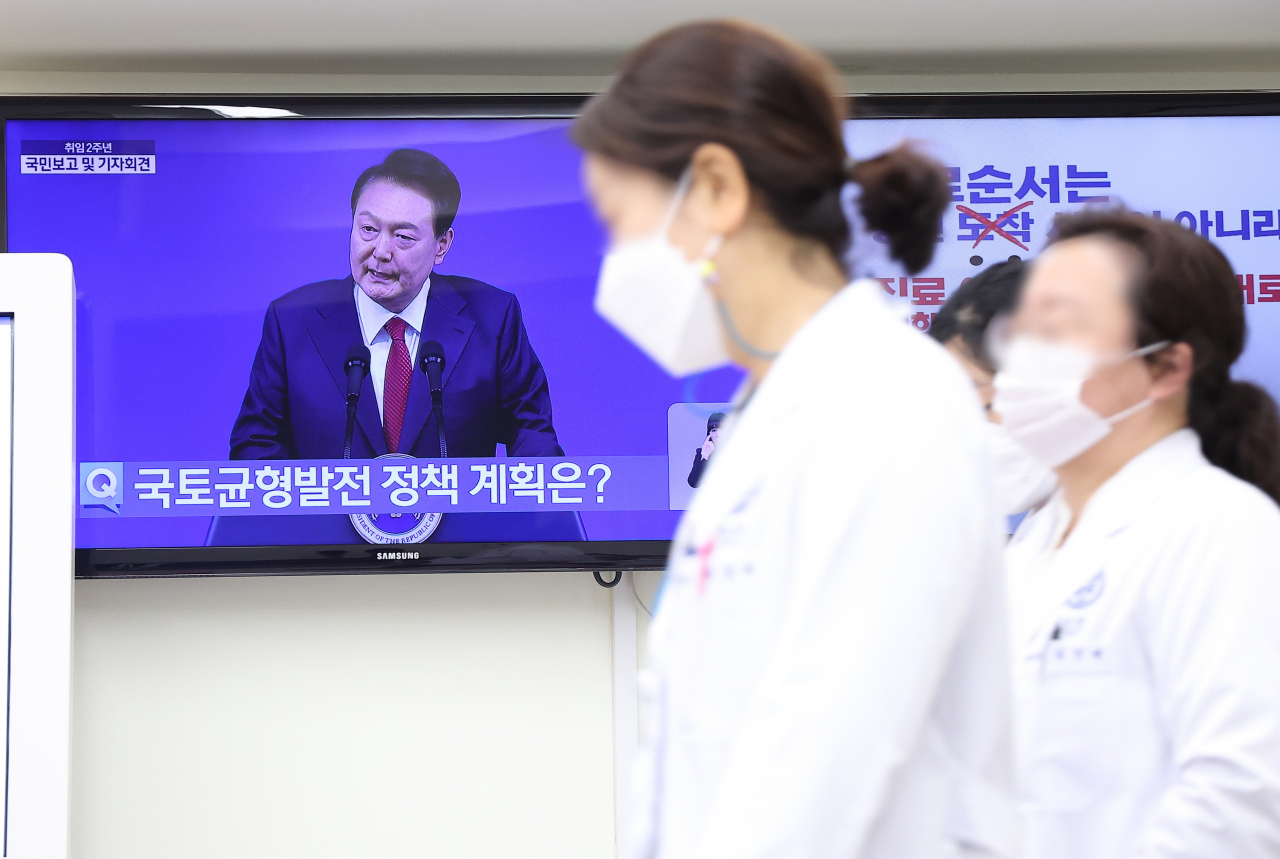 9일 오전 서울 한 대학병원에서 한 의료인이 '윤석열정부 2년 국민보고 및 기자회견'이 생중계되고 있는 텔레비전을 지나치고 있다. [연합]