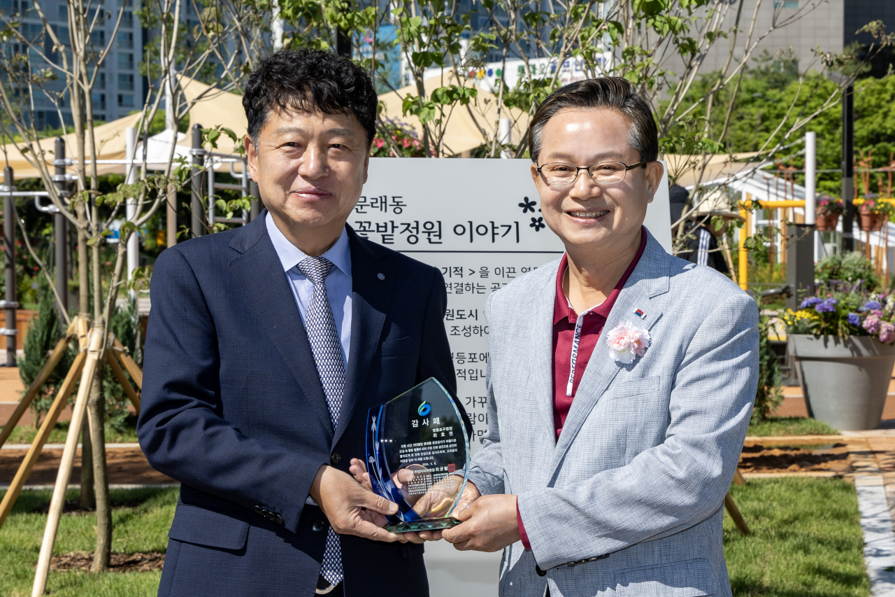 서울 영등포구는 공원, 가로변, 골목길, 하천, 자투리땅 등 일상적 공간 곳곳에 꽃과 나무를 심고 가꾸어 여가를 즐길 수 있도록 정원을 조성해 영등포를 정원도시로 만든다고 22일 밝혔다. 주민들로부터 감사패를 받는 최호권 영등포구청장.[영등포구 제공]