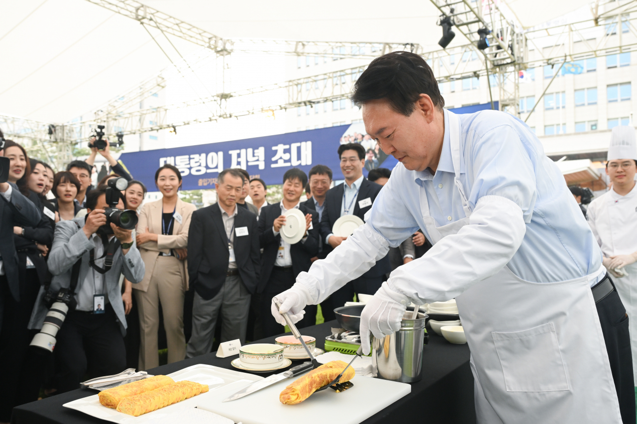 윤석열 대통령이 24일 서울 용산 대통령실 청사 잔디마당에서 열린 '대통령의 저녁 초대' 출입기자단 초청 만찬 간담회에서 계란말이를 만들고 있다. [연합]