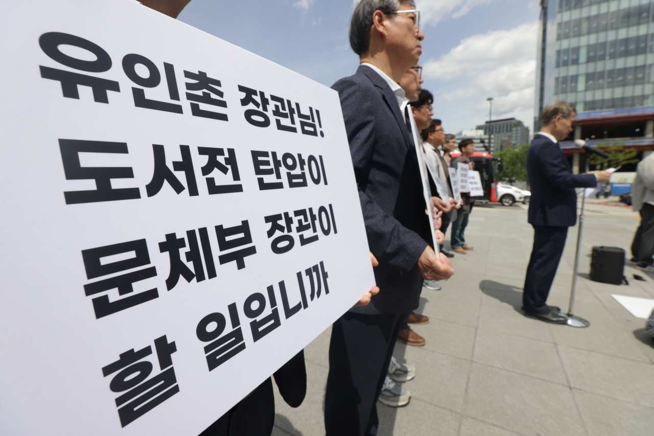 27일 오후 서울 광화문광장 세종대왕 동상 앞에서 열린 대한출판문화협회 '서울국제도서전 문화체육관광부 감사에 대한 행정소송 제기 기자회견'에서 참석자들이 손팻말을 들고 있다. [연합]