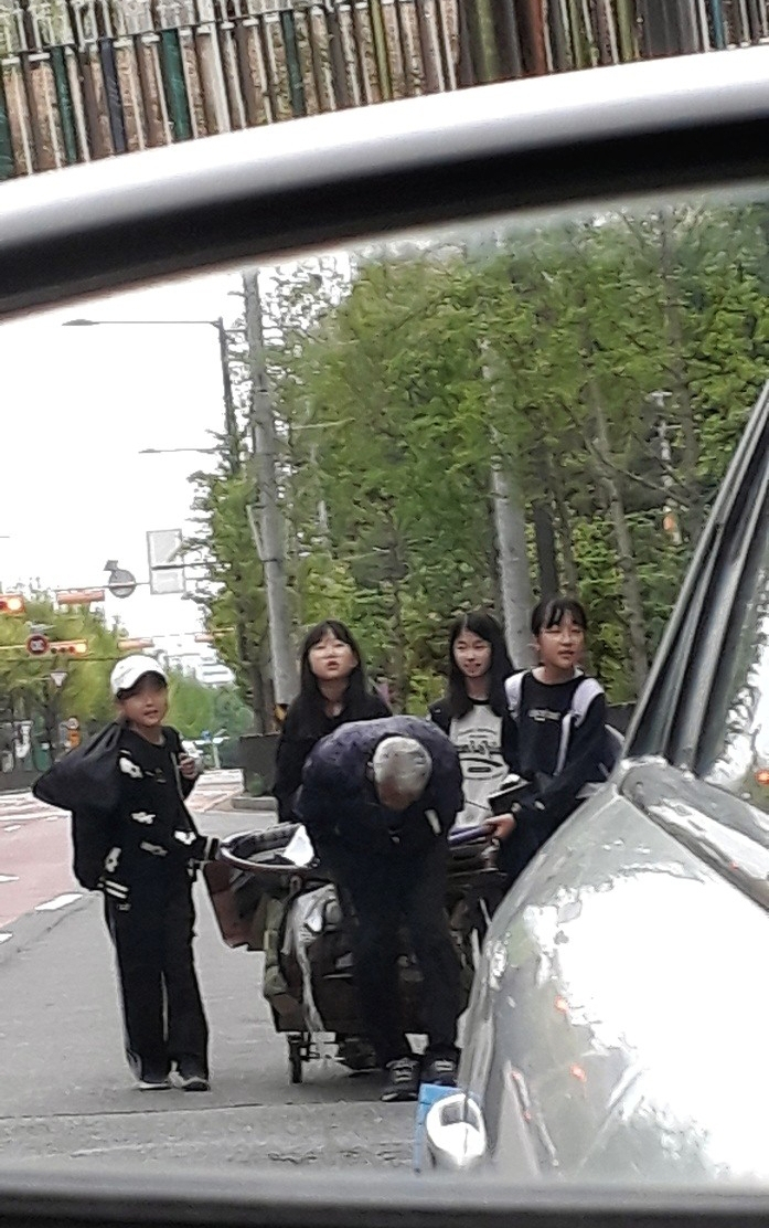폐지 수집 노인의 수레가 넘어지자 달려와 도운 초등학생들의 모습이 한 시민의 차량 사이드 미러에 포착됐다. [연합]