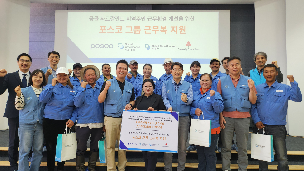 포스코 노사 관계자들이 몽골 주민들에게 구형 근무복을 전달하고 기념사진을 찍고 있다. [포스코 제공]