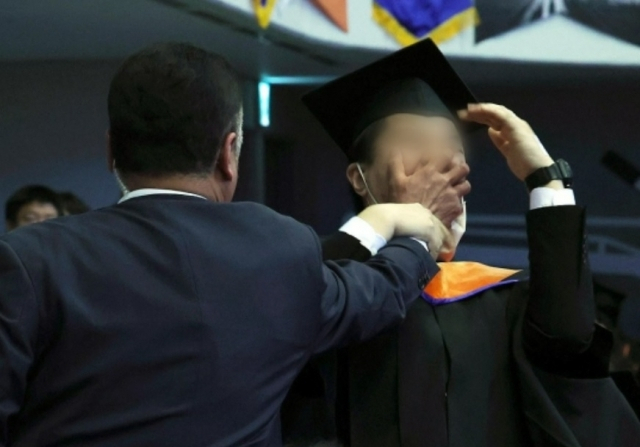 2월 16일 대전 유성구 한국과학기술원(KAIST)에서 열린 2024년 학위수여식에서 한 졸업생이 윤석열 대통령이 축사를 할 때 R&D 예산과 관련해 자리에서 일어나 대통령을 향해 항의를 하던 중 제지를 당하고 있다. [대통령실통신사진기자단]