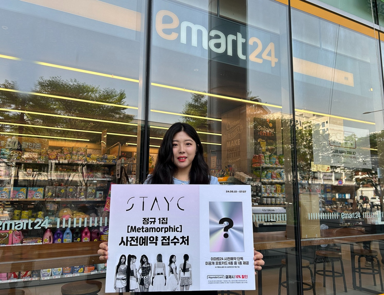 모델이 이마트24 스테이씨 음반 사전예약을 홍보하고 있다. [이마트24 제공]
