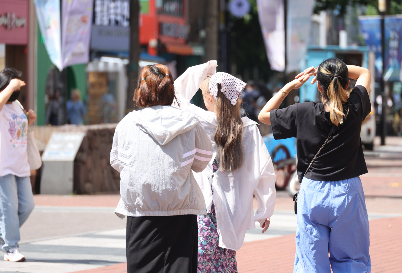 12일 오후 대구 동성로에서 시민들이 손으로 햇빛을 가리며 걷고 있다.[연합]