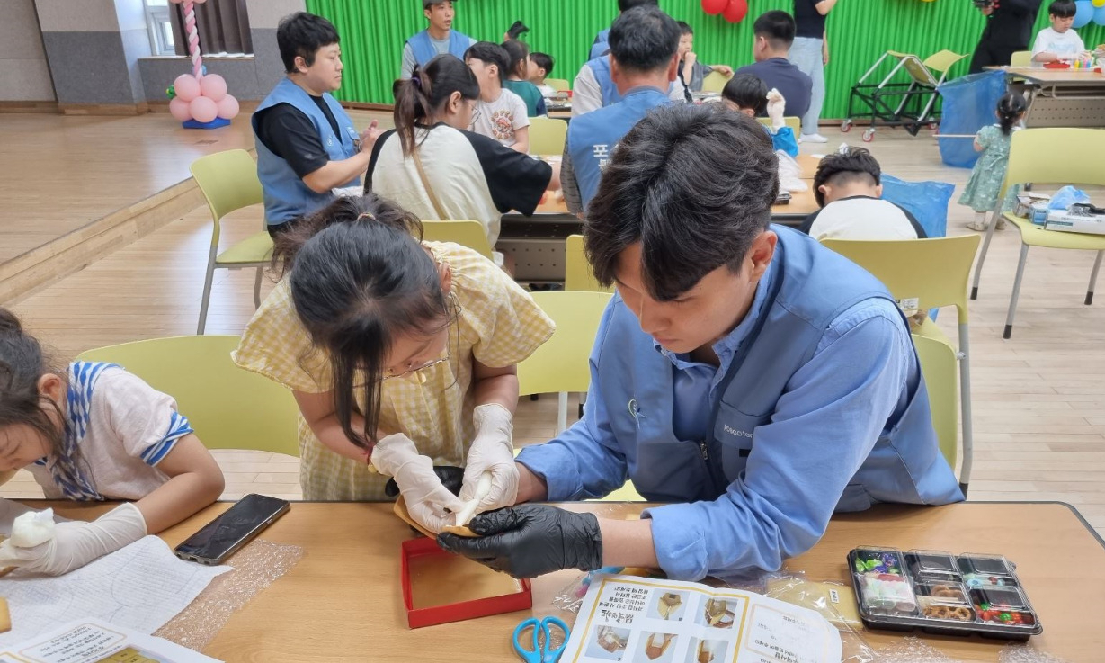 포스코퓨처엠 직원들이 광양 소재 장애인복지관에서 장애아동과 함께 과자집을 만들고 있다. [포스코1%나눔재단 제공]