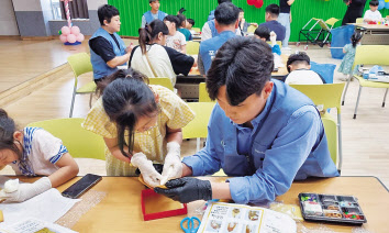 포스코퓨처엠 직원들이 광양 소재 장애인복지관에서 장애아동과 함께 과자집을 만들고 있다.