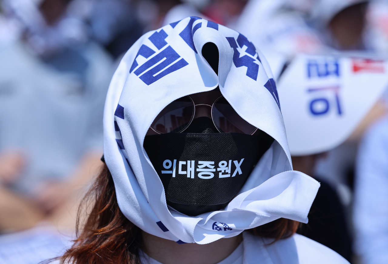서울 한낮 기온이 32도까지 오르며 더운 날씨를 보인 18일 오후 서울 영등포구 여의대로에서 열린 전국 의사 총궐기대회에서 한 참가자가 현수막을 머리에 감고 있다. [연합]