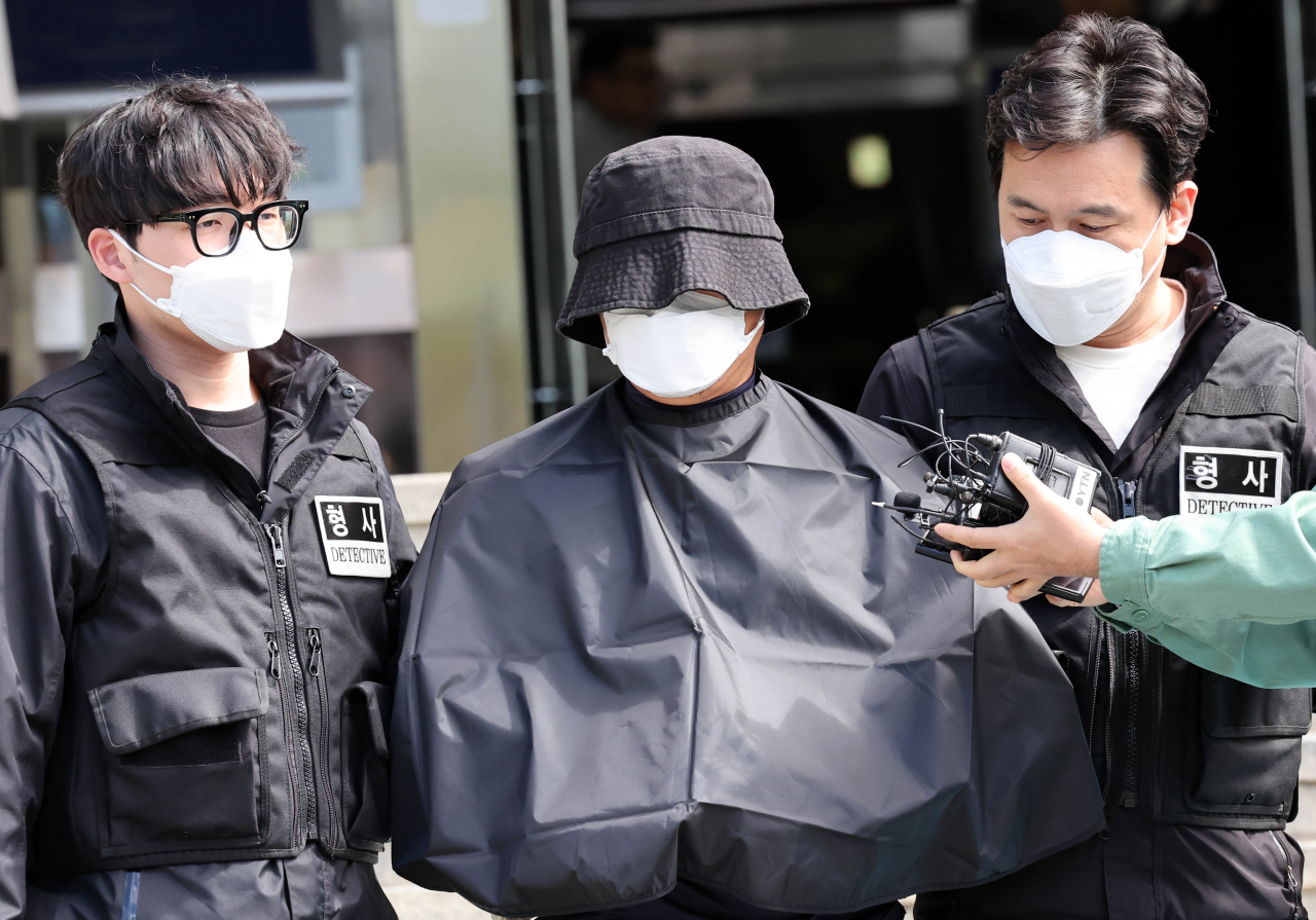 부산 법원 앞에서 흉기로 유튜버를 찔러 살해한 혐의를 받고 있는 50대 남성이 검찰에 구속 송치되기 위해 지난달 16일 오전 부산 연제구 연제경찰서에서 호송차량에 탑승하기 위해 이동하고 있다. [뉴시스]