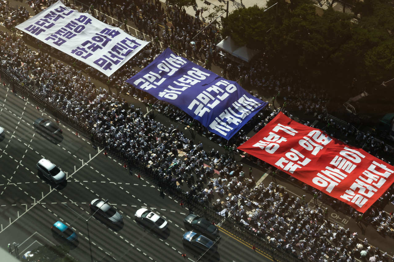 대한의사협회(의협)의 주도로 개원의와 일부 의대 교수들이 집단휴진에 나선 18일 오후 서울 영등포구 여의대로에서 열린 전국 의사 총궐기대회에서 의사들이 '의료농단' 등 문구가 적힌 대형현수막을 펼치고 있다. [연합]