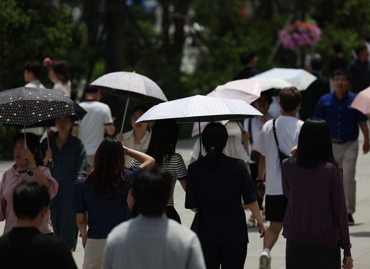 무더위가 이어진 지난 17일 서울 광화문광장에서 우산과 양산을 쓴 시민들이 걷고 있다. [연합]
