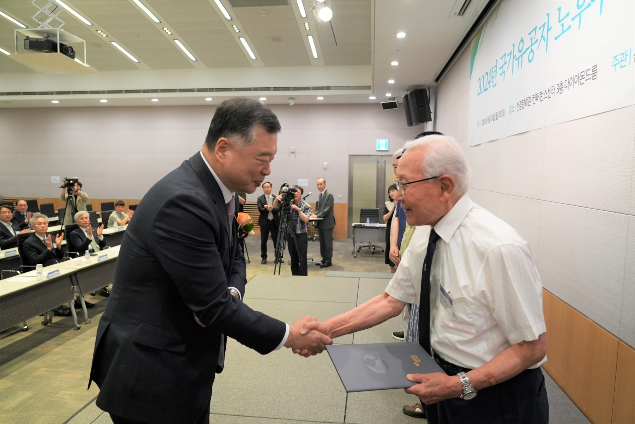 ‘2024년 국가유공자 노후주택보수 및 임차자금지원 기념식’에서 유병태 HUG 사장(왼쪽)이 6.25 참전 유공자(오른쪽)에게 기증서를 전달하고 있다. [주택도시보증공사]