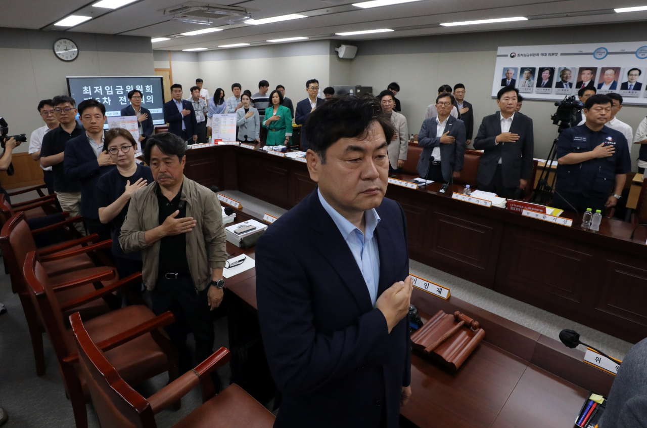 최저임금 법정 심의 기한인 27일 오후 정부세종청사 최저임금위원회에서 열린 전원회의에서 이인재 최저임금위원회 위원장을 비롯한 위원들이 국기에 경례하고 있다. [연합]