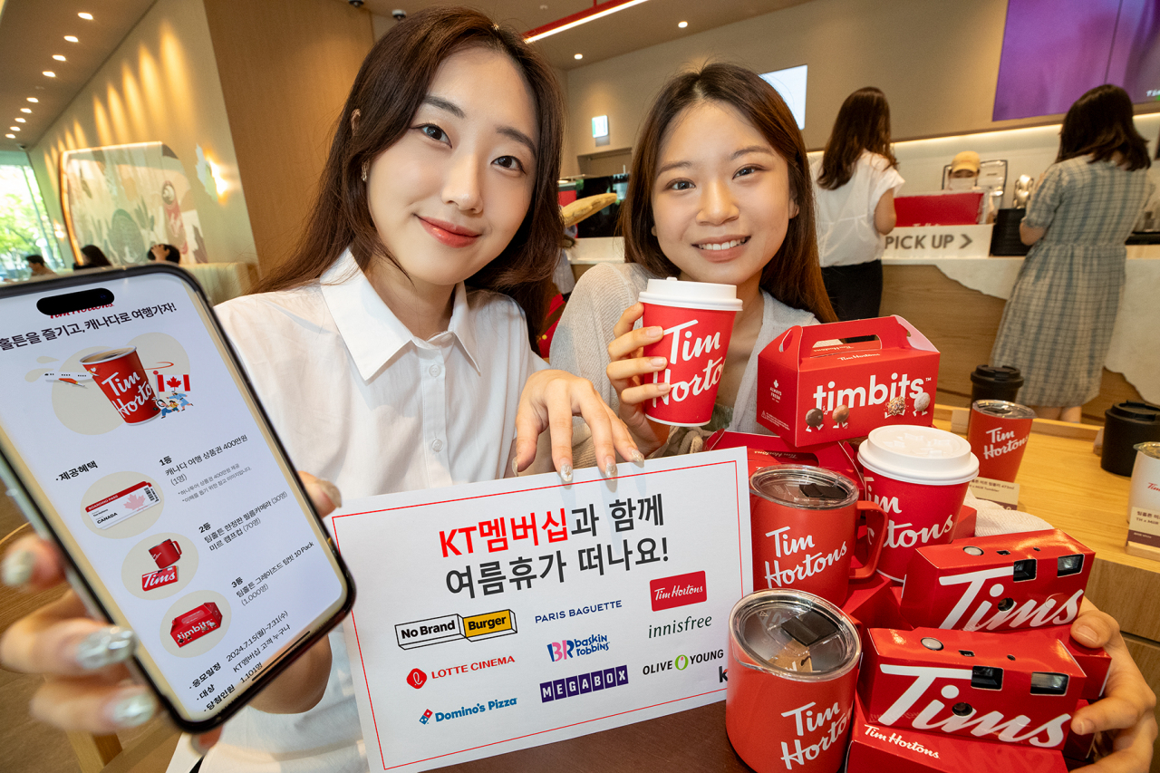 KT 모델들이 광화문에 위치한 카페 ‘팀홀튼’에서 KT 멤버십으로 받은 무료 커피를 즐기고 있다. [KT 제공]