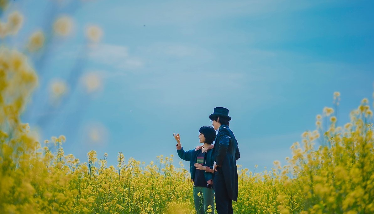 A still image shows Ah-yi and magician Ri-eul standing in a canola flower field in "The Sound of Magic." (Netflix)