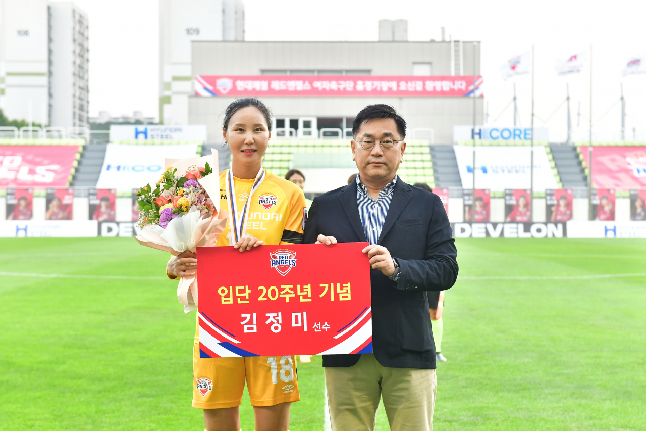 지난 4일 인천남동럭비경기장에서 김정미 선수의 입단 20주년 기념 행사가 열렸다. 서상원 현대제철 레드엔젤스 단장이 꽃다발을 전달하고, 김정미 선수와 기념 촬영을 하고 있다. [현대제철 제공]
