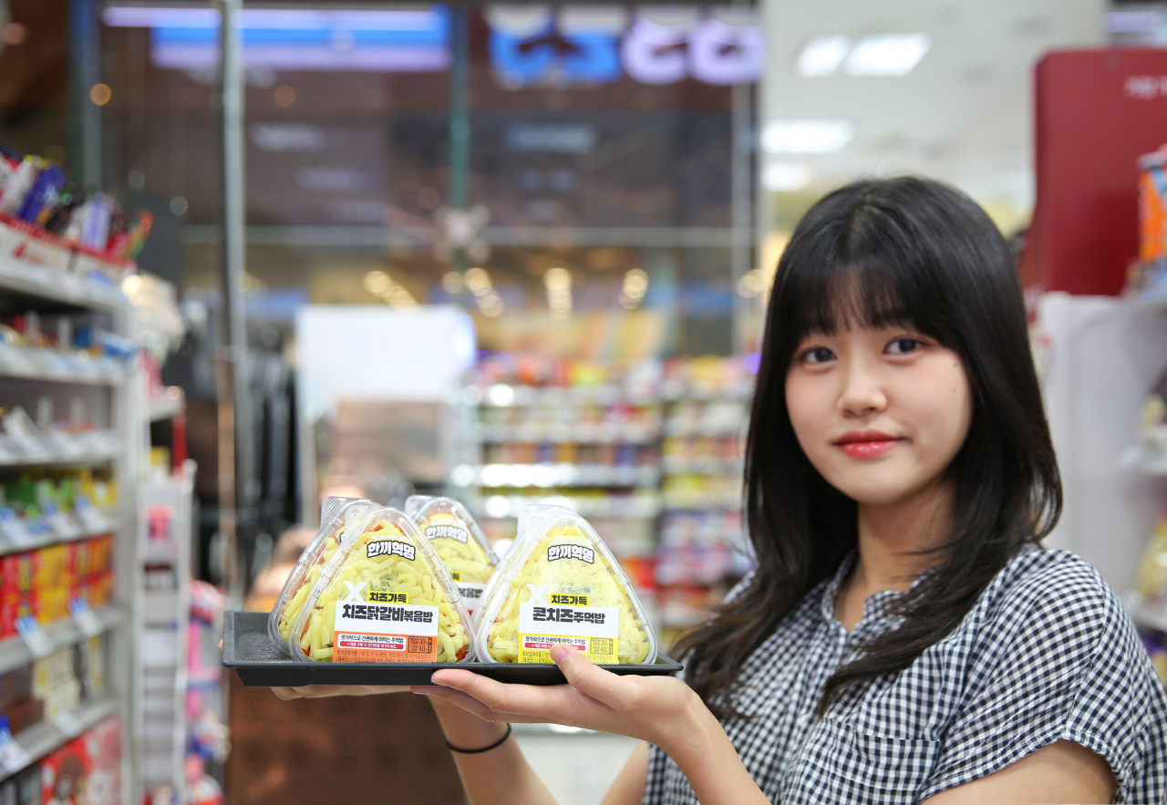 모델이 GS25에서 속 보이는 '치즈닭갈비볶음밥'과 '콘치즈주먹밥'을 들고 있다. [GS리테일 제공]