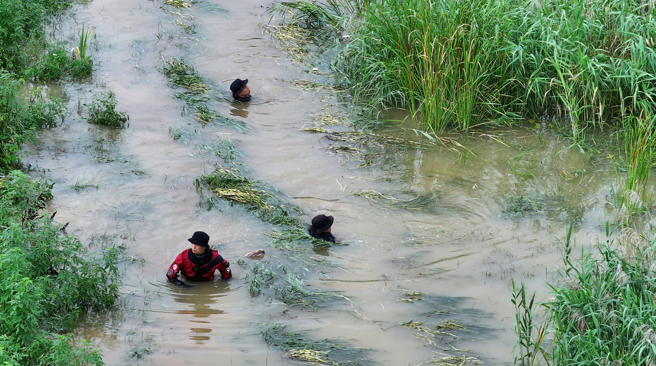 Firefighters search for a missing person in her 40s following heavy rain in Gyeongsan, 250 kilometers southeast of Seoul, on Tuesday. (Yonhap)