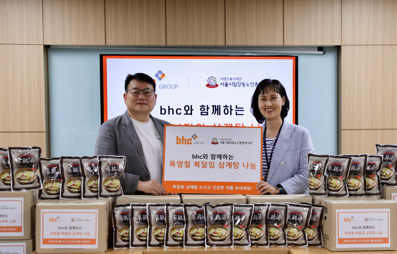 지난 9일 종합외식기업 bhc 그룹이 초복을 앞두고 서울시립 강동노인종합복지관을 찾아 사랑의 삼계탕 나눔 행사를 진행했다. 문상만 bhc 가맹사업본부장(왼쪽)이 성미선 서울시립 강동노인종합복지관 관장에게 삼계탕을 전달한 후 기념촬영을 하고 있다.