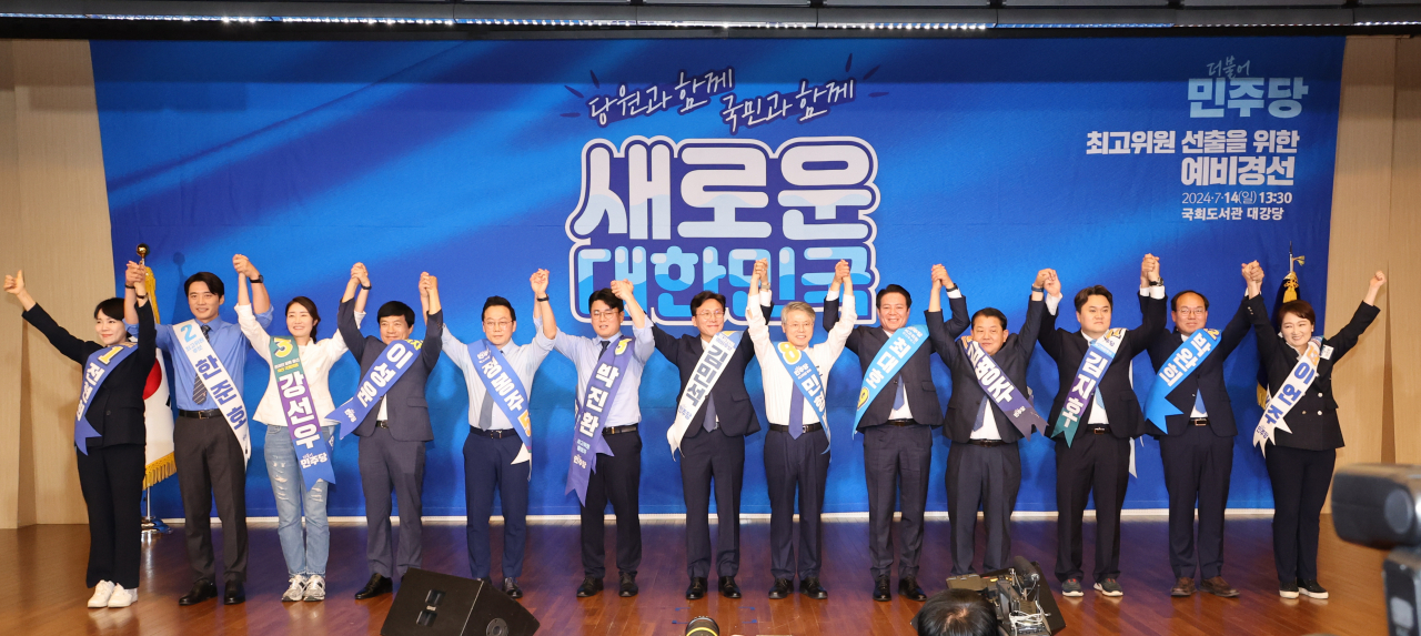 14일 오후 서울 여의도 국회도서관 강당에서 열린 더불어민주당 8·18 전당대회 최고위원 선출을 위한 예비경선. 13명의 후보자들이 정견 발표에 앞서 손을 들어올리며 당원들에게 인사하고 있다. 왼쪽부터 여섯번째가 박진환 예비후보. [연합]