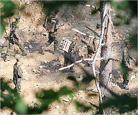군 관계자는 17일 “북한군이 최근 수개월 동안 지뢰 수 만발을 마구잡이식으로 매설하고 있다”며 “남북 공유하천에서 집중 호우시 의도적 기습 방류와 지뢰살포 또는 유실 가능성에 유의해야 한다”고 밝혔다. 사진은 우리 군 당국이 관측한 북한군 작업 모습. 북한군이 군사분계선 인근에서 지뢰를 등에 지고 매설하며 이동하고 있다.[국방부 제공]