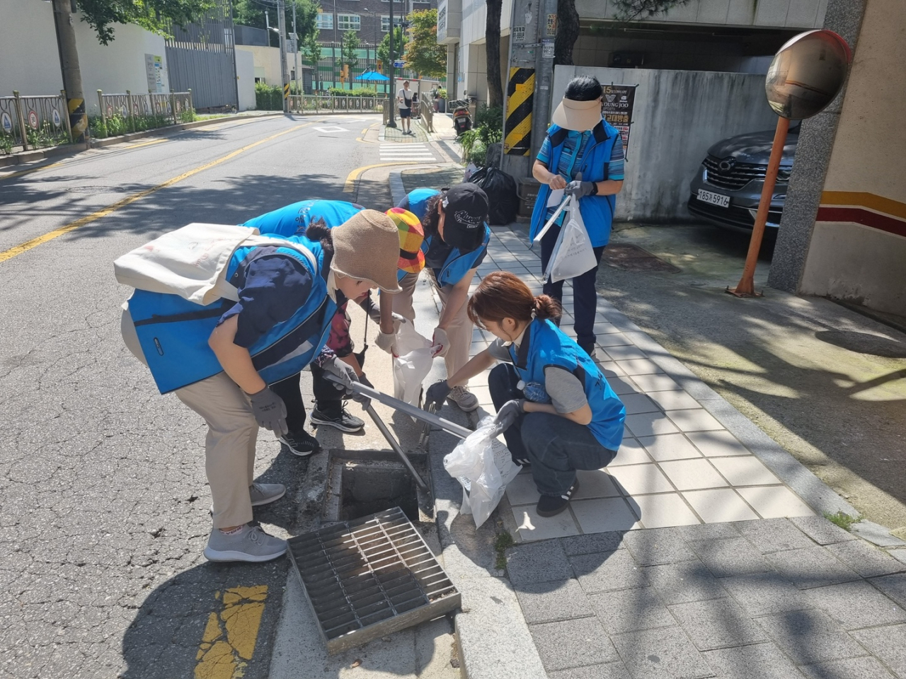 서울시자원봉사센터 소속 관계자들이 빗물받이에 쌓인 담배꽁초, 낙엽 등을 제거하고 있다.[서울시 제공]