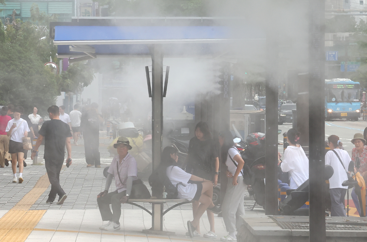 횡단보도 인근에 시민들이 쿨링포그(인공안개 분사시설) 아래에서 더위를 식히고 있다. 연합뉴스