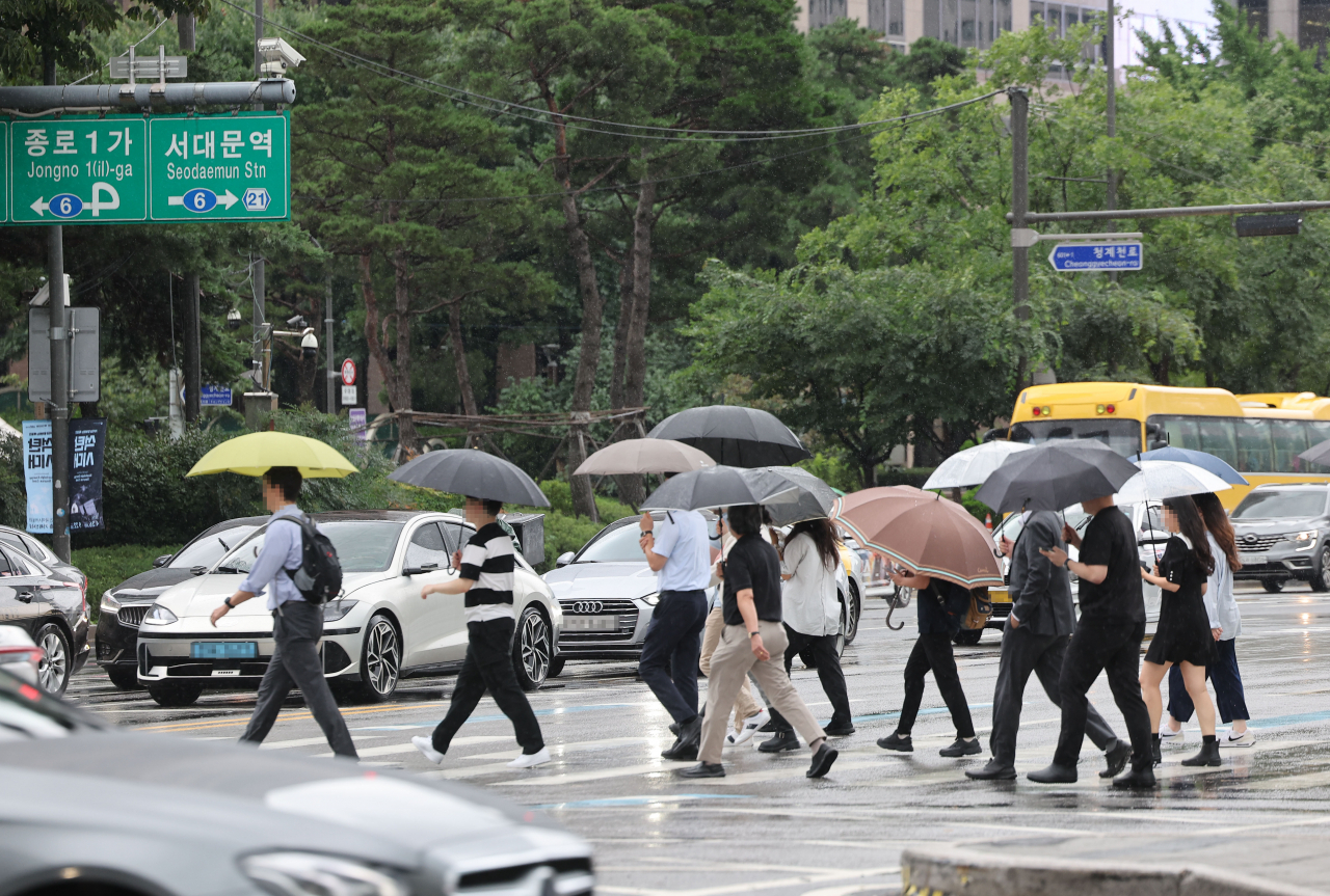장맛비가 이어진 23일 우산을 쓴 시민들이 서울 광화문 사거리를 지나고 있다. [연합]