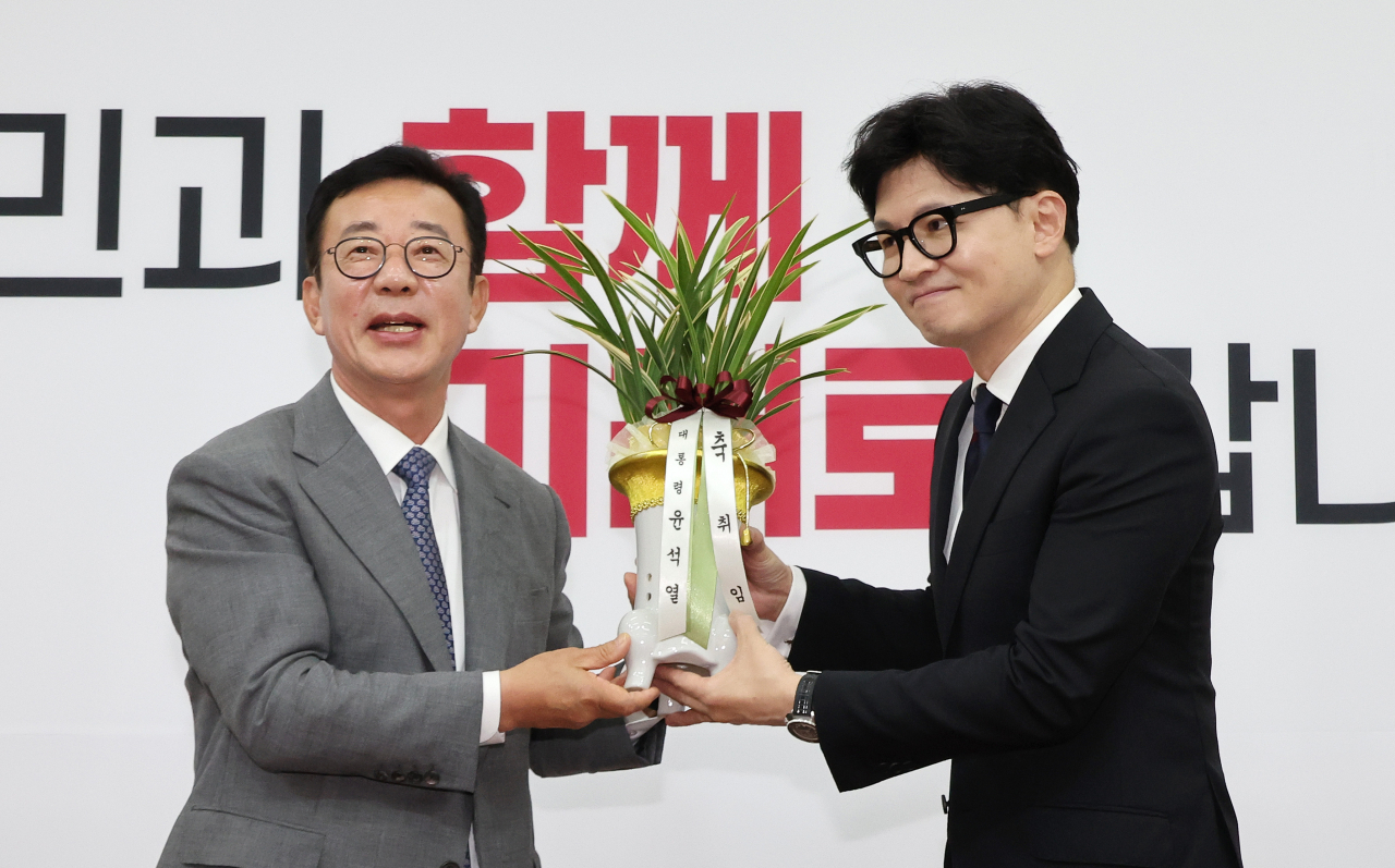 한동훈 국민의힘 신임 대표가 24일 오후 국회를 예방한 홍철호 대통령실 정무수석(왼쪽)으로부터 윤석열 대통령의 축하 난을 받고 있다. [연합]
