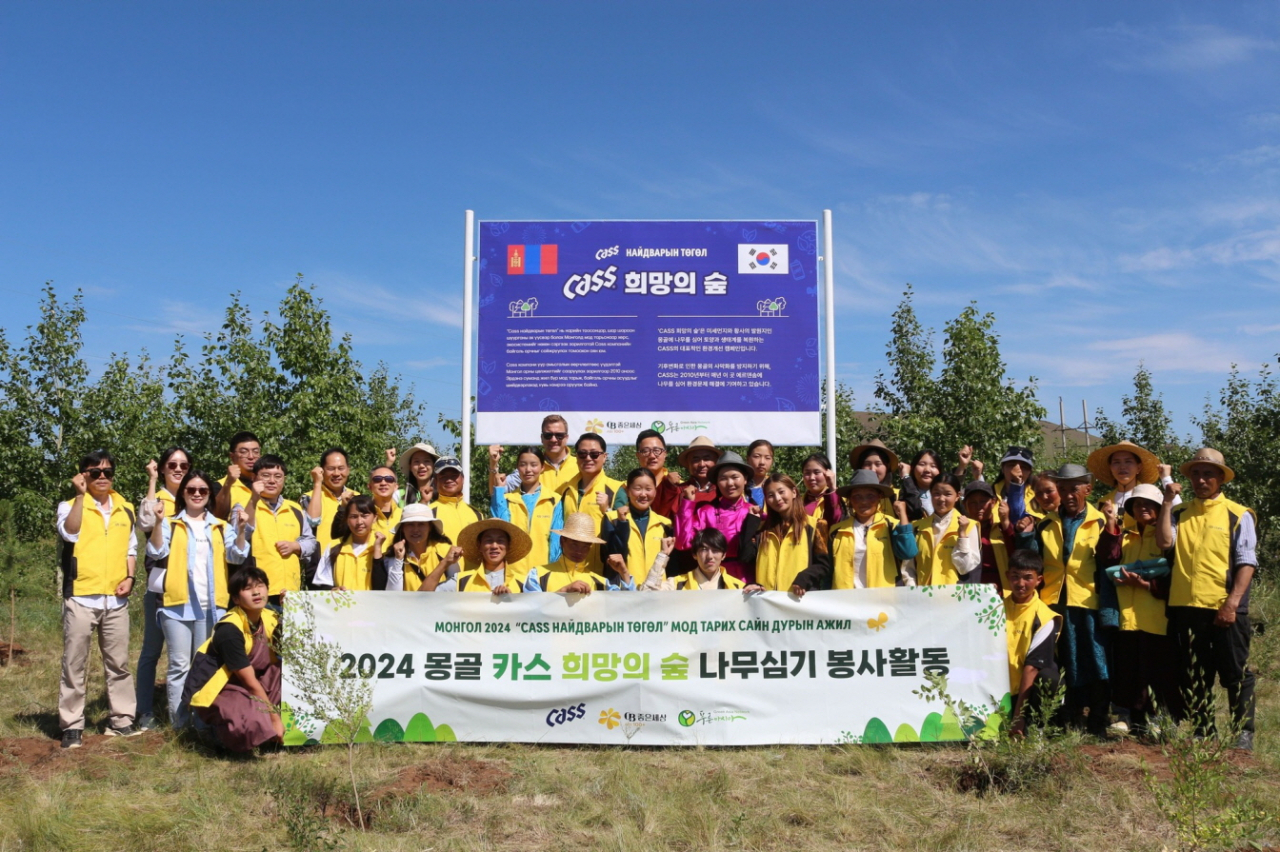 지난 24일 오비맥주 임직원이 푸른아시아 관계자, 몽골 환경난민 등으로 구성된 봉사단과몽골 ‘카스 희망의 숲’ 기념 현판 앞에서 나무심기 봉사활동을 마치고 기념사진을 찍고 있다. [오비맥주 제공]