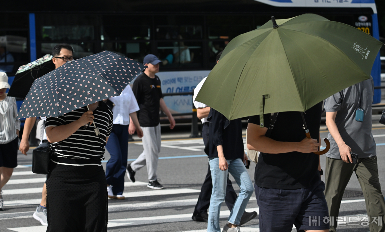장마가 끝나고 전국적으로 폭염특보가 발효된 31일 오전 서울 종로구 세종대로사거리에서 양산을 쓴 시민들이 출근길을 서두르고 있다. 임세준 기자