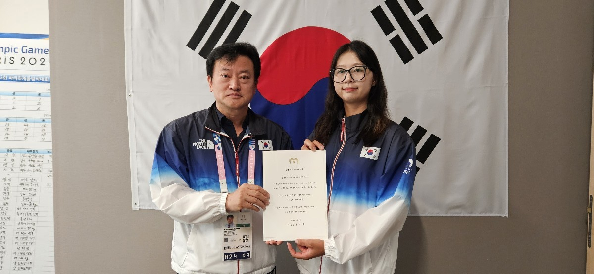 5일(현지시간) 양궁, 수영, 사이클 종목 선수들의 퇴촌식에서 정강선 단장이 양궁 임시현에게 윤석열 대통령의 축전을 전달하고 있다. [정강선 단장 제공]