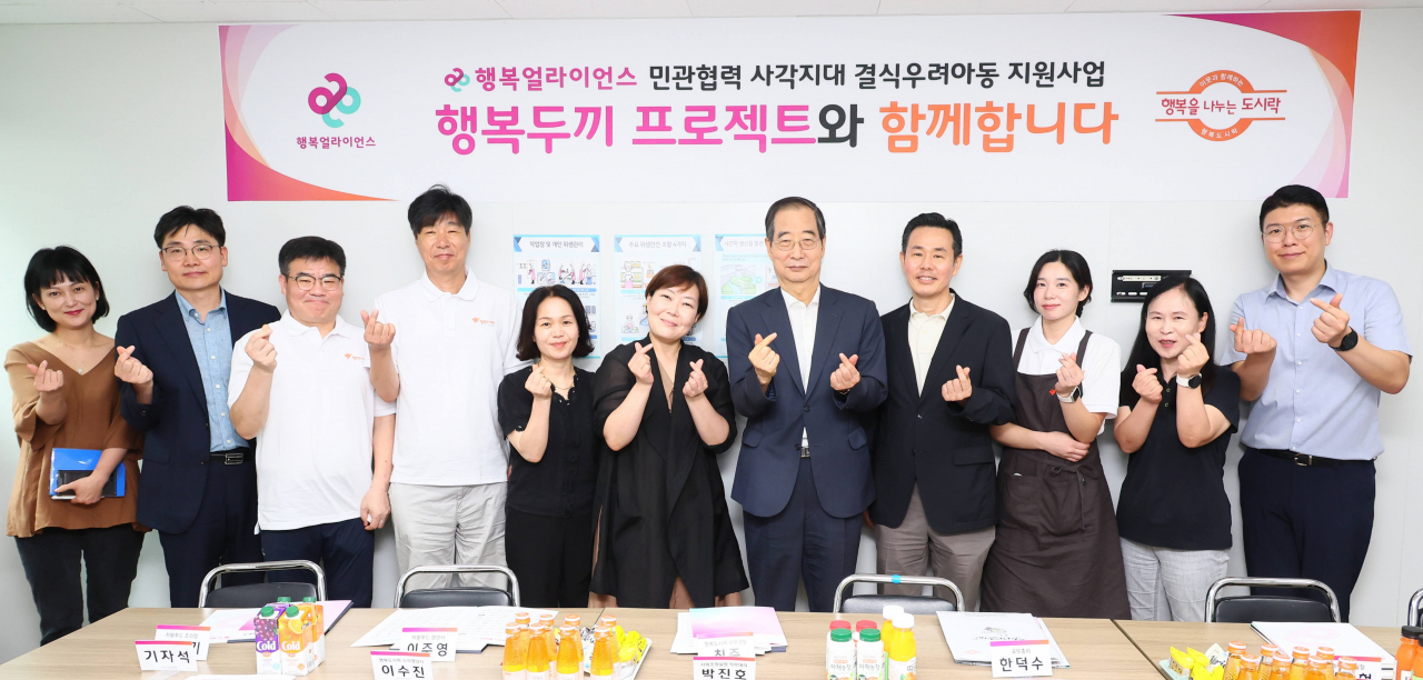 한덕수(오른쪽 다섯 번째) 국무총리가 8일 서울 성북구 행복도시락센터에서 조민영(오른쪽 네번째) 행복얼라이언스 본부장 등과 기념촬영을 하고 있다. [행복얼라이언스 제공]