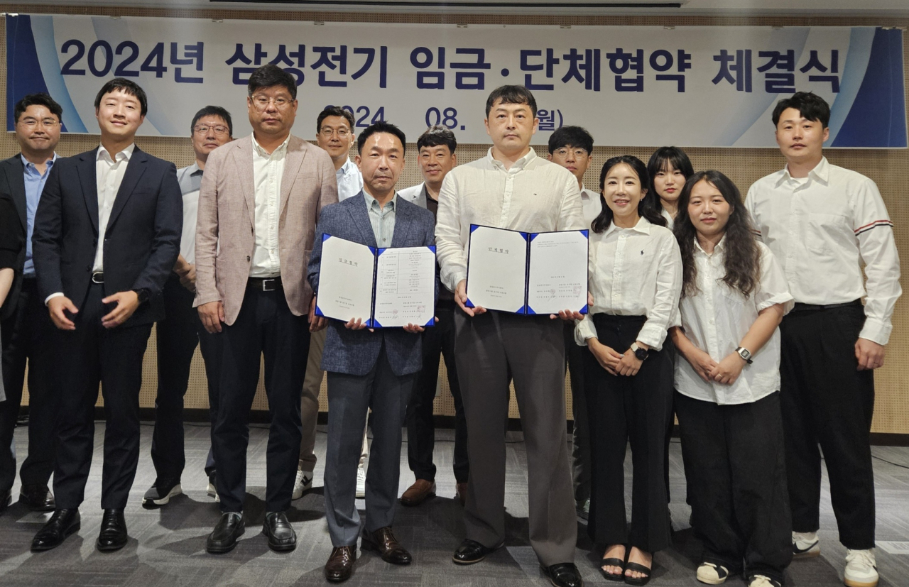 박봉수(앞줄 왼쪽 세 번째부터) 삼성전기 피플팀장(부사장)과 신훈식 존중노종조합지부장이 지난 12일 수원 컨벤션센터에서 열린 ‘2024년 임금협약 체결식’에서 기념촬영을 하고 있다. [삼성전기 제공]