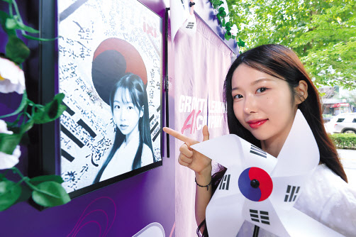모델이 LG유플러스 서울 마포구 도화동 공덕역점에서 광복절 콘셉트의 인공지능(AI) 프로필 사진을 제작해주는 ‘익시 포토부스’를 체험하고 있다. [LG유플러스 제공]