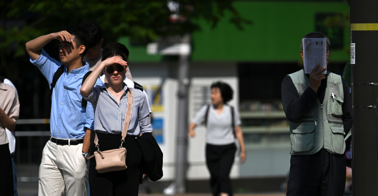 초여름 날씨를 보이고 있는 14일 오전 서울 종로구 세종대로 사거리에서 시민들이 손과 신문으로 햇빛을 가리며 출근길을 서두르고 있다. 기상청에 따르면 이날 전국 대부분 지역의 최고 체감 온도가 31도 이상 오르는 등 무더위가 이어질 것으로 보인다. [임세준 기자]