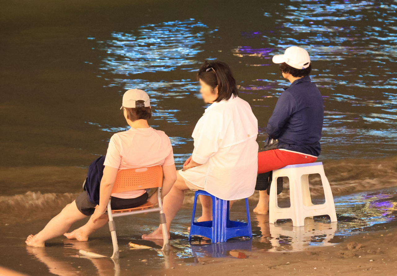 부산에 역대 최장인 21일 연속 열대야가 나타난 15일 오후 부산 수영구 광안리해수욕장에 많은 시민이 모여 바닷바람을 맞으며 더위를 이겨내고 있다. [연합]