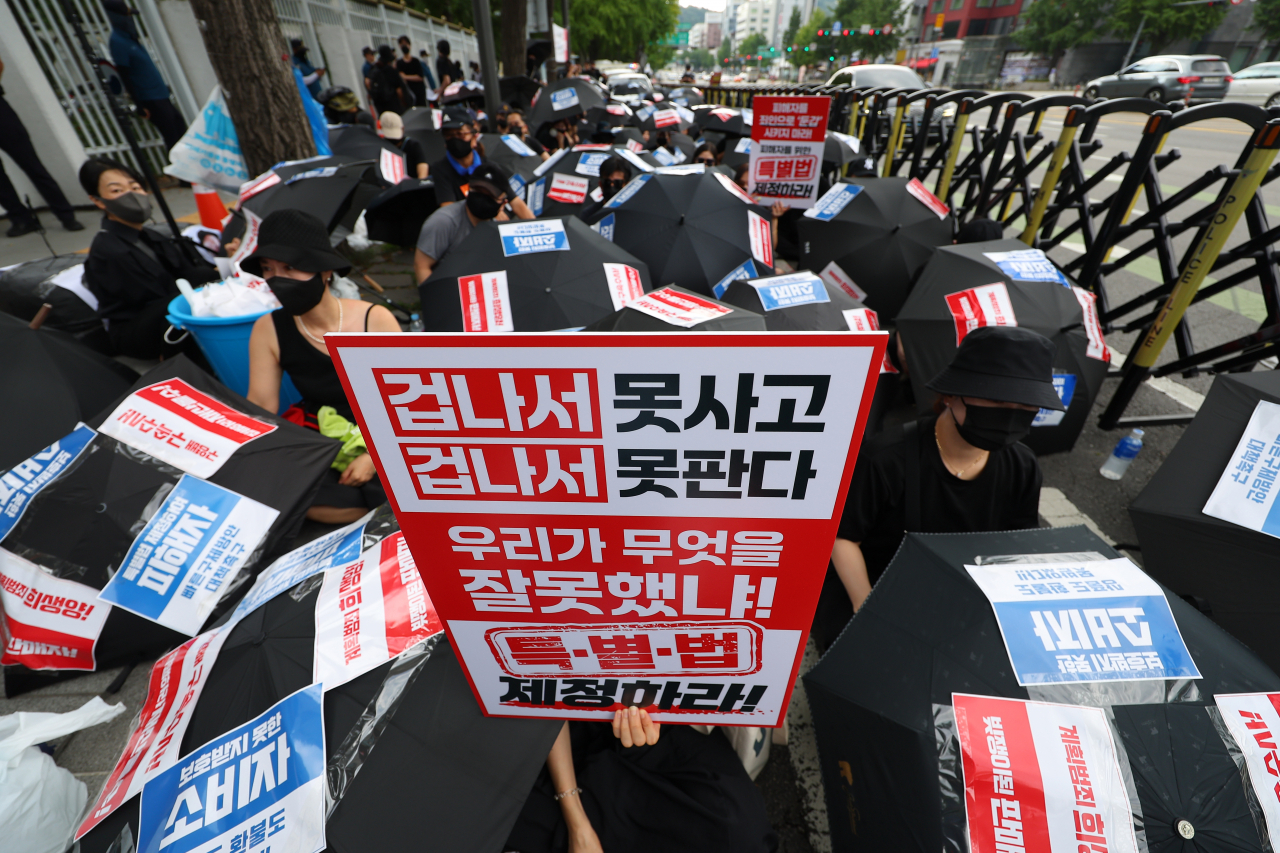 티몬·위메프(티메프) 피해 판매자와 소비자들이 지난 18일 오후 서울 종로구 금융위원회 앞에서 열린 ‘검은 우산 집회’에 참가해 우산을 펴고 자리에 앉아 있다. [연합]