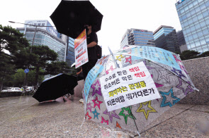 티몬·위메프(티메프) 피해자가 5일 서울 중구 대한상공회의소 인근에서 카드사와 전자지급결제대행사(PG사)들에 즉각 환불을 촉구하는 릴레이 우산 시위를 하고 있다. [연합]