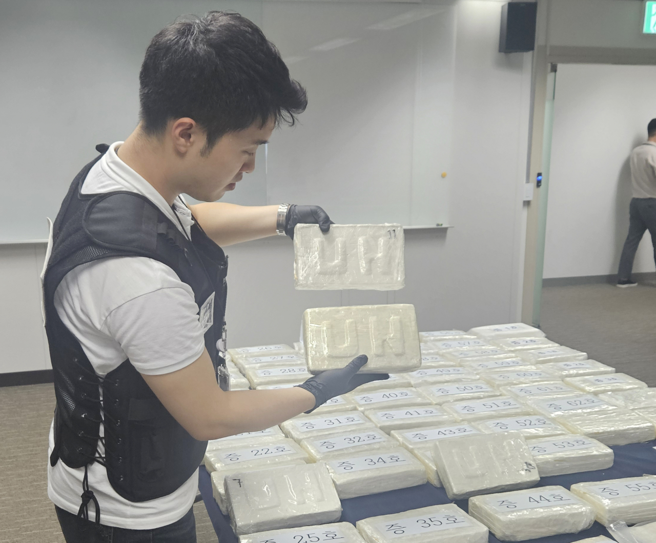 해양경찰관이 19일 오전 중부지방해양경찰청에서 열린 코카인 밀반입 일당 검거 브리핑에서 캐나다 밴쿠버의 마약 조직을 뜻하는 'UN'이라고 적힌 마약을 들고 있다. 연합뉴스