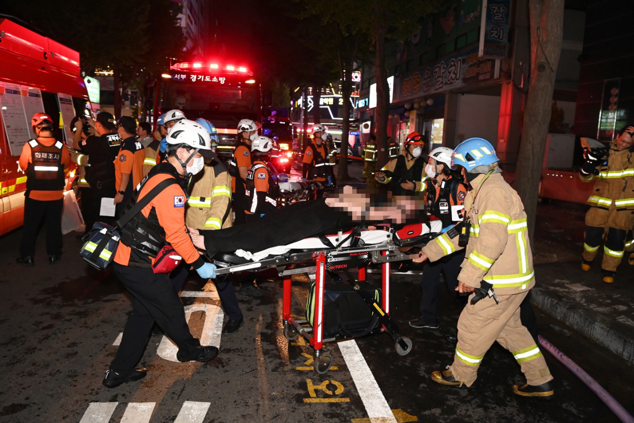22일 오후 경기 부천 모 호텔의 화재 현장에서 소방대원들이 환자를 이송하고 있다. 이 불로 7명이 숨졌고 다른 투숙객 등 12명이 다쳤다. [연합]